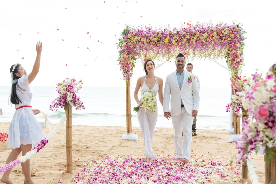 An amazing spring beach wedding of purple, pink and yellow. Ocean and beach background with floral pergola.